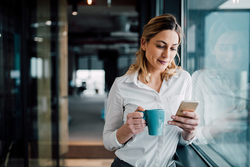 woman drinking coffee reading phone