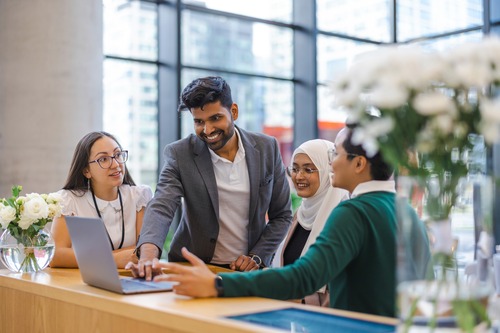 group of four people looking at a laptop