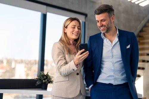 Two people, a man and a woman, smiling and talking about the reasons to bring in temp workers