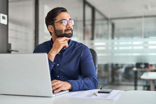 A businessman looking away and smiling while thinking about outplacement and new trends of 2025