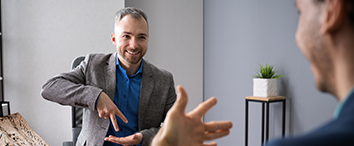 Picture of two man sitting and talking, showing the signs with their hands