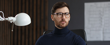 Picture of man with glasses sitting in office chair with white lamp next to him