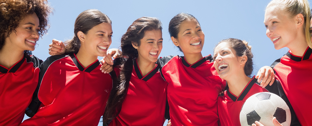 Picture of female football team hugging and smiling