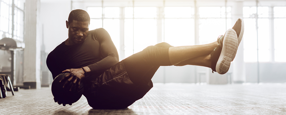 Picture of young man exercising with the ball on the floor