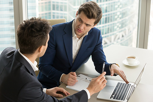 two-serious-businessmen-using-laptop-discussing