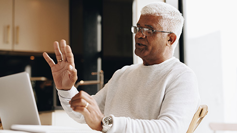 A senior businessman gesturing in front of a laptop