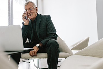 A senior businessman smiling in front of a laptop