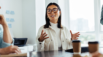 A businessman gesturing and talking in an office team meeting